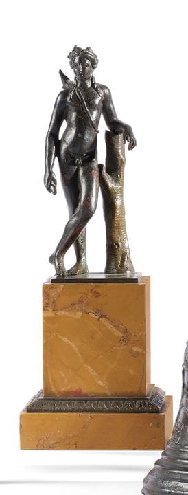 A bronze statue of Eros with a dark patina. Depict