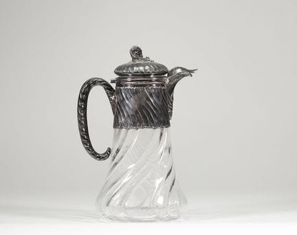 水晶与银制水壶，约1900年
带盖水壶，壶身采用模压水晶制成，饰有宽大的扭纹。醒目的银制壶架饰有螺旋