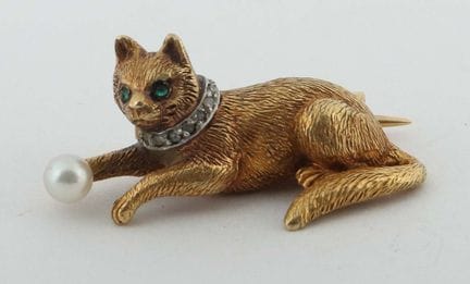猫形胸针，20世纪，750黄金打造的猫形胸针，猫爪握着一个球，项圈镶嵌玫瑰色钻石，眼睛镶嵌绿色宝石，