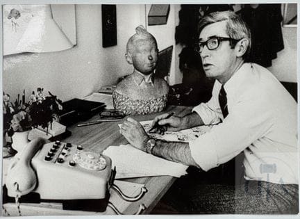 Hergé / Portrait du maître à son bureau avec le bu