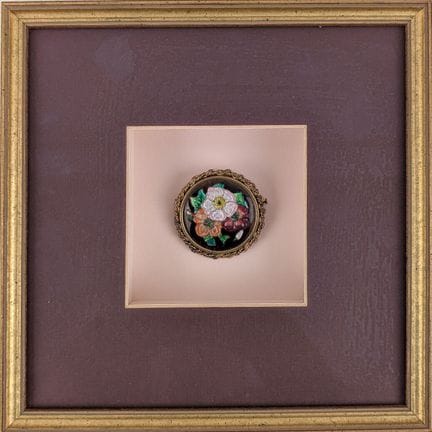 Emaillierte Brosche mit Blumenmotiv in einem Glasr