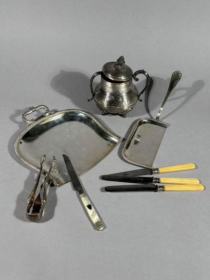 一套镀银的金属餐具，包括：
- 两把餐勺。
- 一个带盖的糖罐（表面有凹凸纹理）。
- 一把糖夹。
