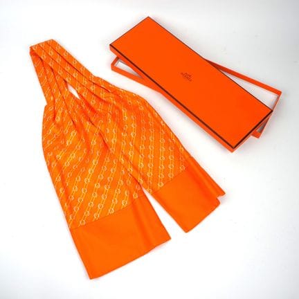 HERMES. Ascot en soie orange, motif fer à cheval.
