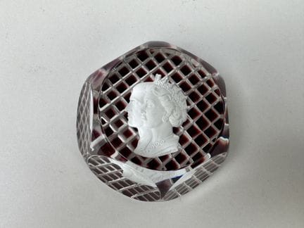 Faceted glass paperweight featuring royal profiles