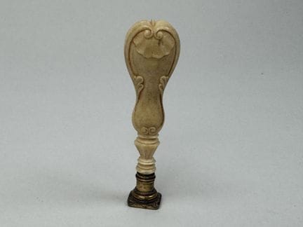 A seal made of synthetic ivory; the die is of gild