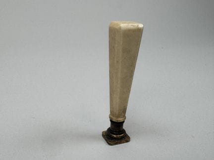 A seal made of synthetic ivory; the die is of gild