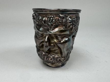 Silver plated metal cup with a raised satyr design
