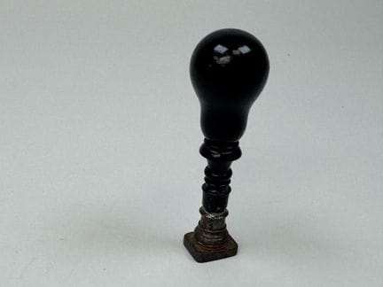 Turned and blackened wooden seal; the metal die is