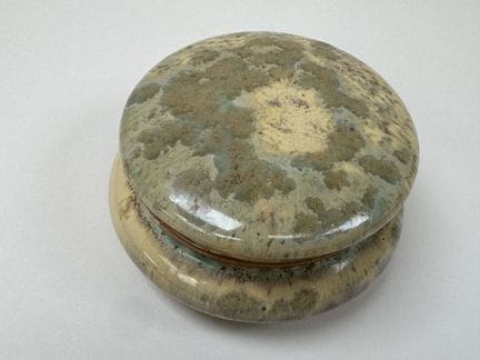 皮埃尔丰，20世纪初。
一件小型圆形釉面石质糖果盒，浅绿色和黄色底色上饰有图案。
背面有标记。
直径