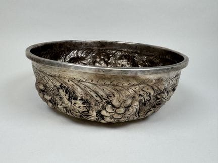 Round metal bowl with repoussé decoration featurin