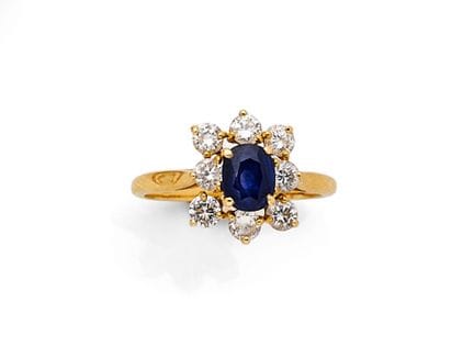 18K（750‰）黄金雏菊戒指，中央镶嵌一颗约6×5毫米的椭圆形刻面蓝宝石，周围环绕八颗小圆形明亮式