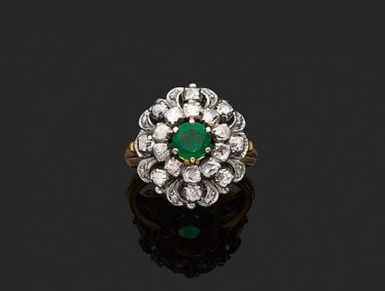 18K（750‰）黄金与白金戒指，饰有抽象花卉图案，中央镶嵌一颗圆形刻面祖母绿，周围环绕着玫瑰式切割