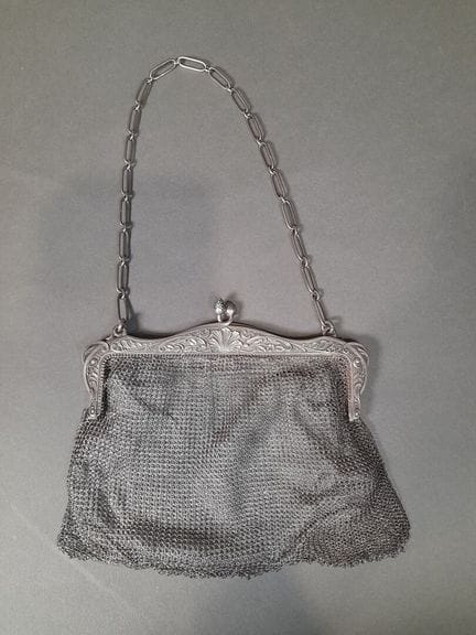 Bolsa de limosna de plata con un asa; el cuerpo es