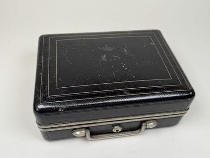 A small black leather and metal travel case; the l