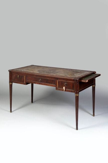 A flat mahogany-veneered desk with three drawers s