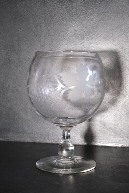 一款吹制水晶葡萄酒杯，杯身雕刻有葡萄藤图案。
高：25 厘米。直径：14 厘米。

由于本次拍卖采用