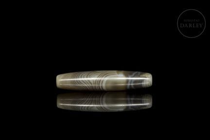A Dzi-style ritual bead with a stylized form and r