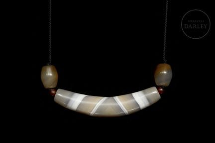 A pendant consisting of a large central Dzi with a