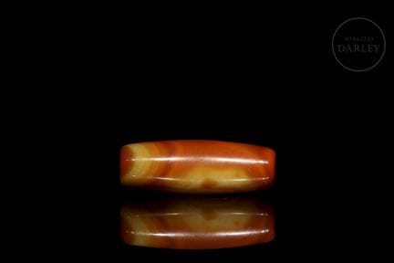 A natural agate bead with a cylindrical, rounded p
