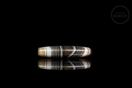 A delicate amulet bead with an elongated profile, 