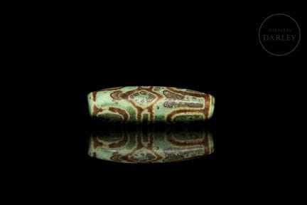 An elongated Dzi-style bead (གཟི།), carved from mi