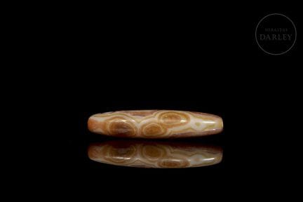 An elongated, spindle-shaped amulet carved from ag
