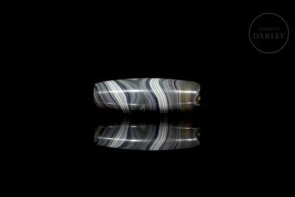 An elongated, spindle-shaped Dzi-style ritual bead