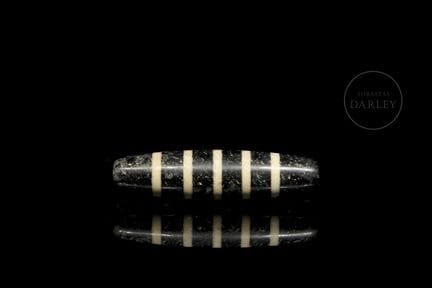 Bead carved from black agate with ivory-colored de