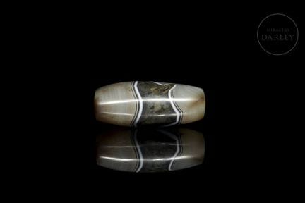 A large, solid, spindle-shaped ritual bead carved 