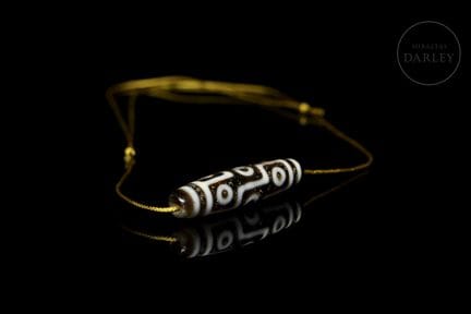 An elongated, spindle-shaped amulet carved from da