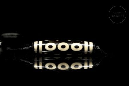 Ritual bead made of black agate with ivory-toned d