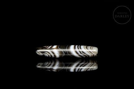 An elongated bead, finely polished from natural ve