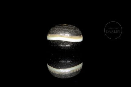 A spherical, black-hued agate ritual bead. It has 