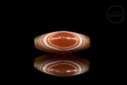 A natural agate bead in a vibrant red color with t