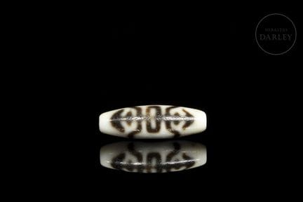 A ritual bead made of agate with an ivory-colored 
