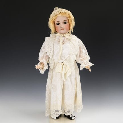 Blondes Puppenmädchen in weißem Kleid. Kämmer & Re