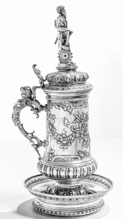 19世纪后期德国银制啤酒杯。约1880年。杯身置于圆形底座上，采用浮雕工艺饰有洛可可风格图案，把手呈
