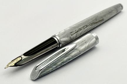 一支Waterman C/F白金属钢笔。法国制造，配有18K金笔尖。笔身和笔帽采用机刻纹白金属材质，