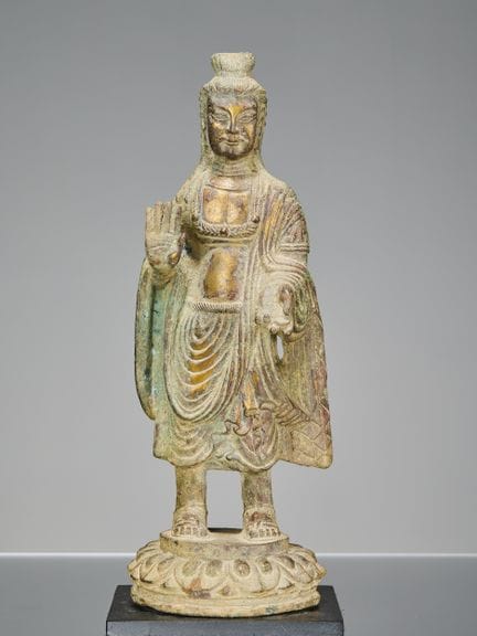 UN ANTICO BUDDHA IN BRONZO IN POSIZIONE ERETTA IN 