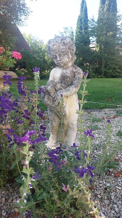 Garden statue. Cast stone. 20th century. Putto wit