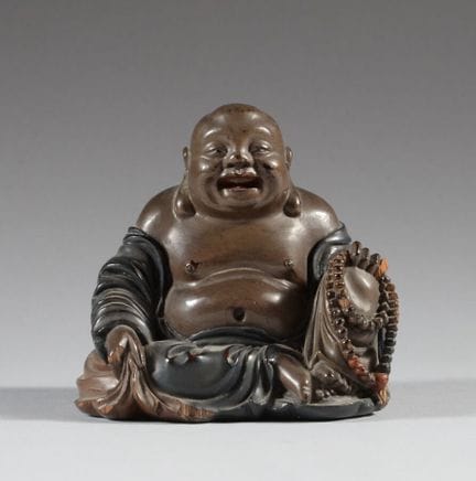 中国
漆木制布袋和尚小雕像，呈坐姿，面带微笑，身着宽松长袍，上身赤裸，手持一个袋子和一串念珠。
20