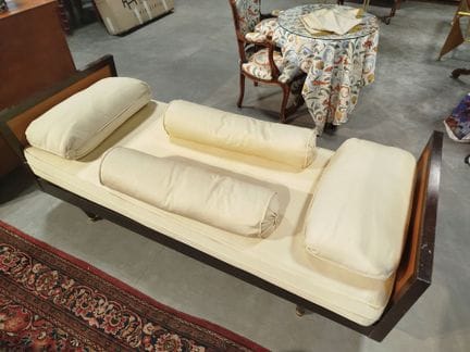 A daybed made of stained wood and light-colored wo