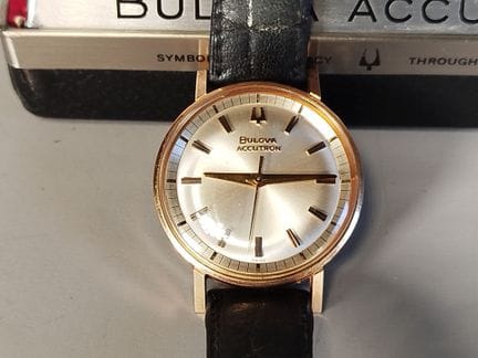 BULOVA：Accutron电子音叉机芯腕表，金色金属圆形表壳，浅色表盘配棒形时标，表背设有调时装
