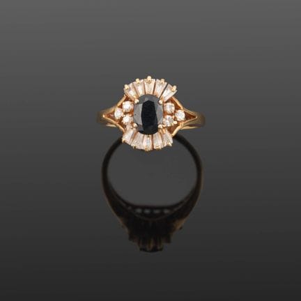 Anello in metallo dorato con una pietra blu sfacce