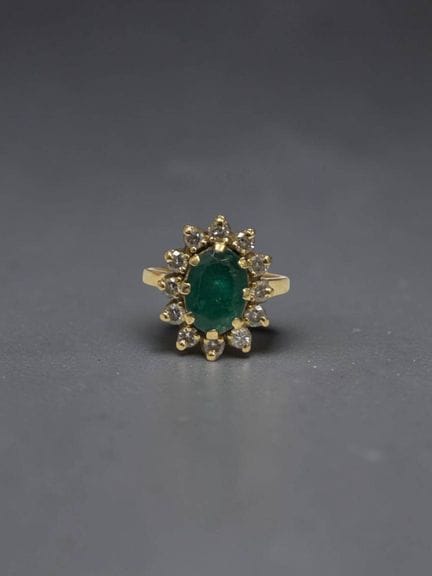 Daisy ring set with an oval emerald surrounded by 