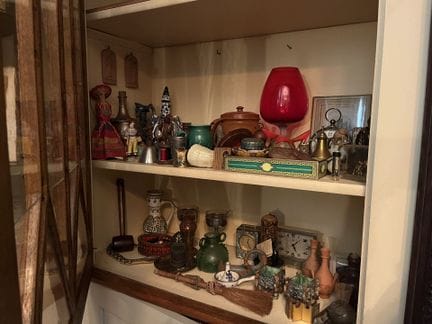 在左侧玻璃柜的两个下层架子上：
一套各式各样的物品，均为度假纪念品，包括陶器和瓷器制品、部分木雕作品
