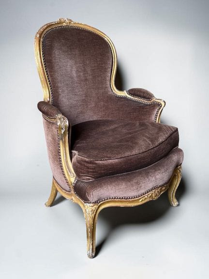 A wooden bergère chair with molded, carved, and gi
