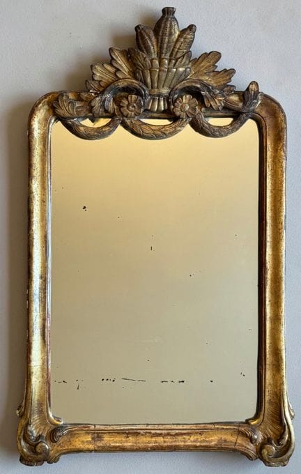 Gilded wooden mirror topped with a basket, decorat