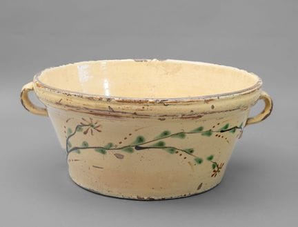 * 碗
釉面陶器，底色为浅黄色，点缀着绿色、棕色和深棕色。器身呈截锥形，口沿带有浮雕纹饰，两侧各有一