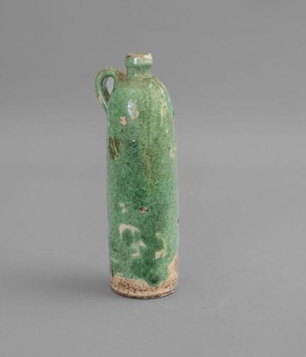 * Botella
De barro esmaltado con fondo verde. Cuer